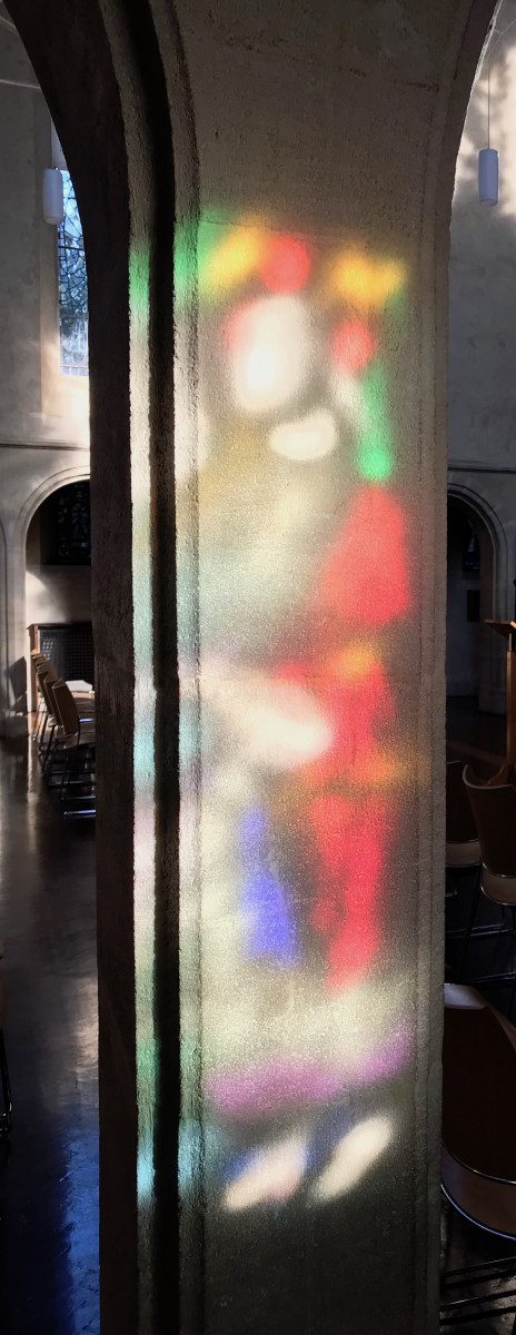 Sunlight through stained glass shines on stone wall
